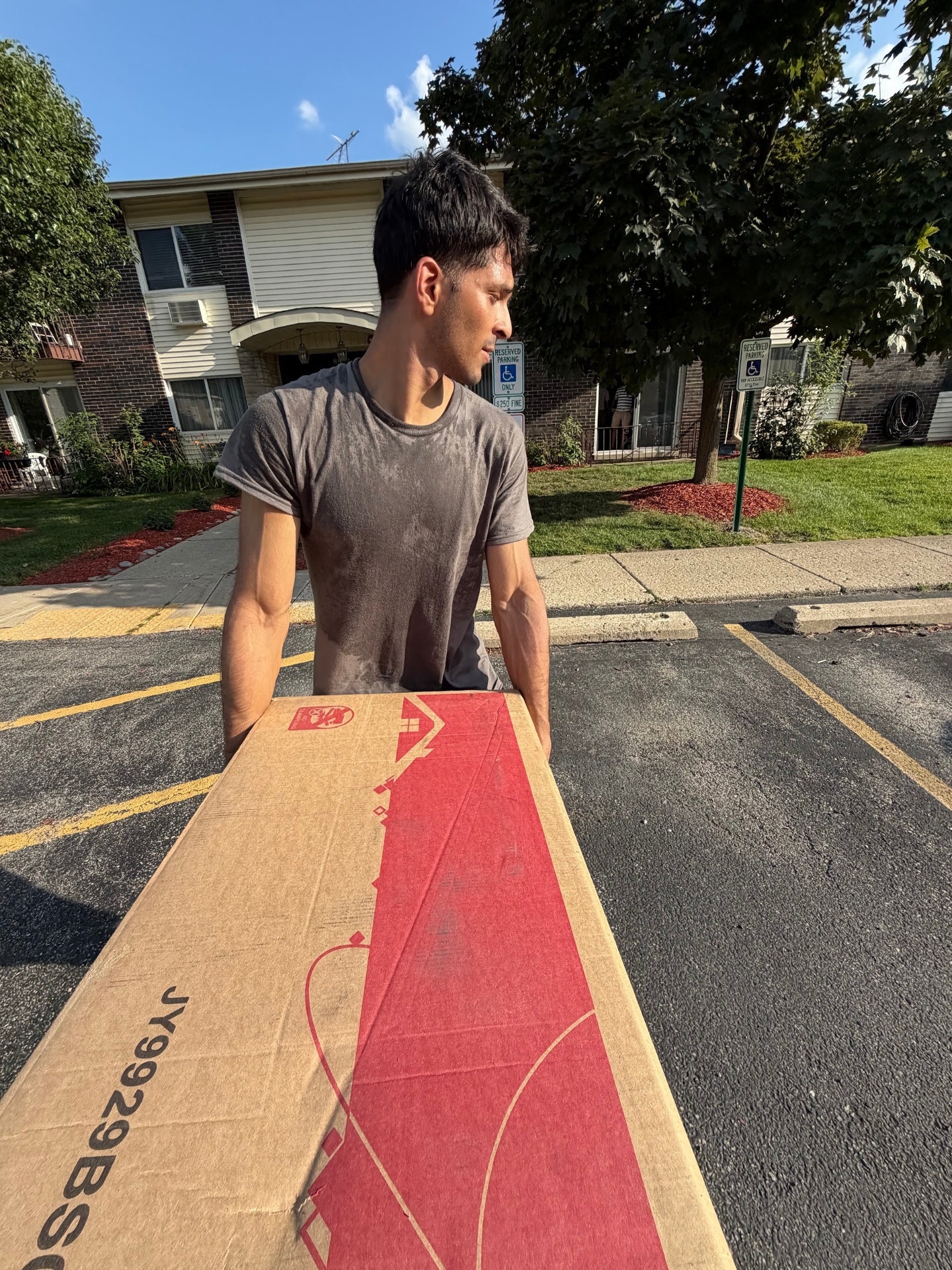 Loader carrying a large boxed item to a residential building
