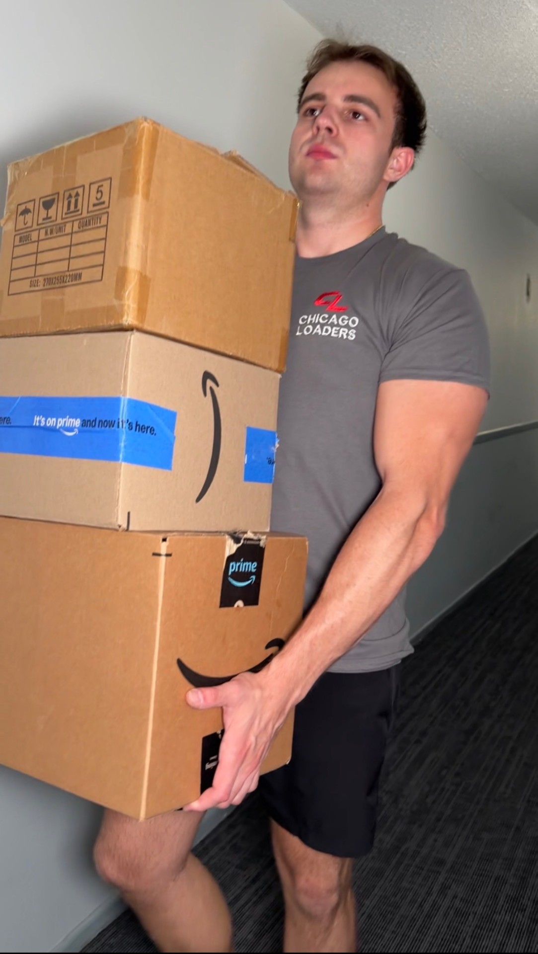 Loader carrying a stack of packages down a hallway