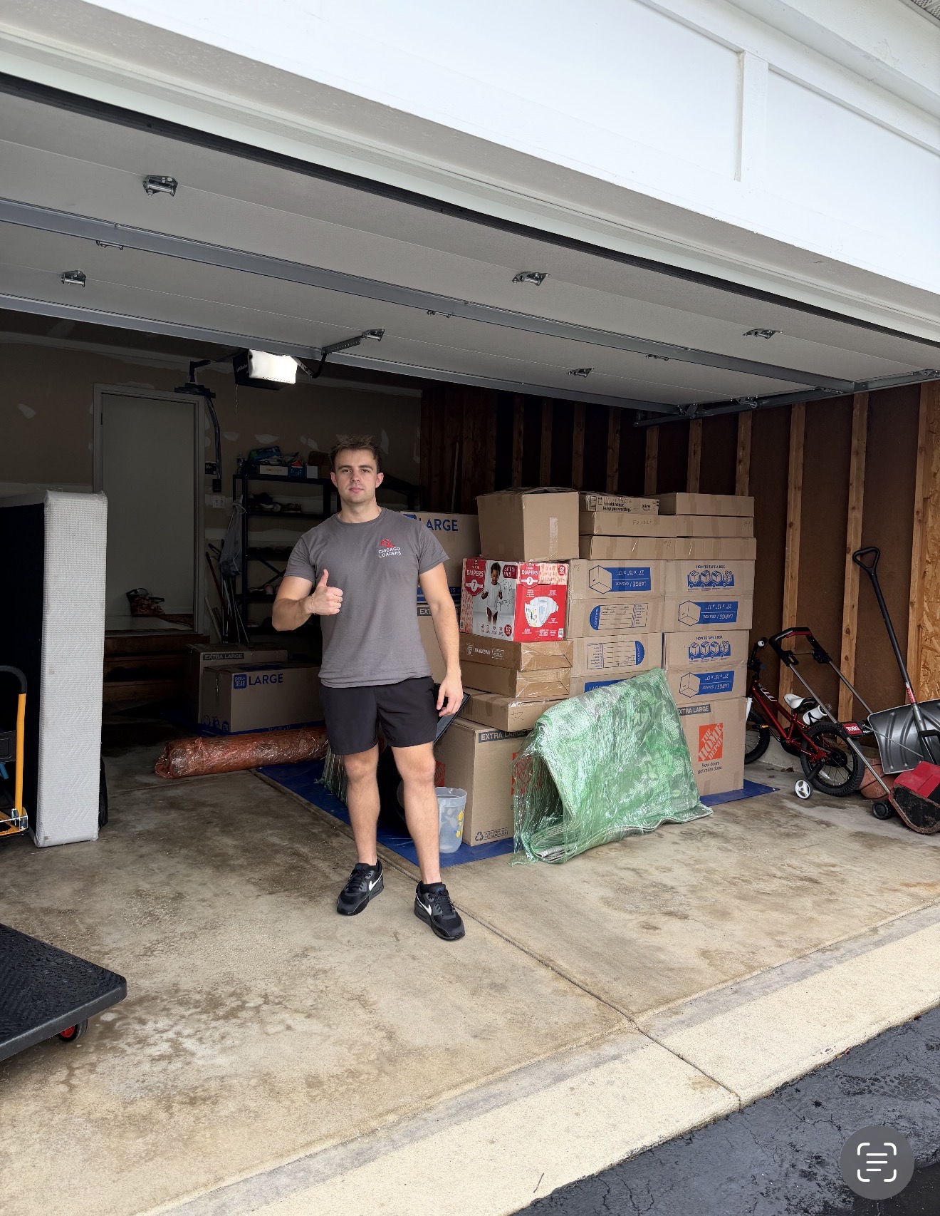 Mover giving a thumbs up in front of an organized garage full of packed boxes