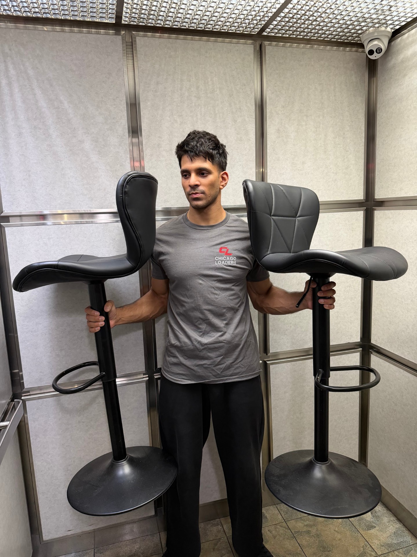 Loader carrying two bar stools out of an elevator