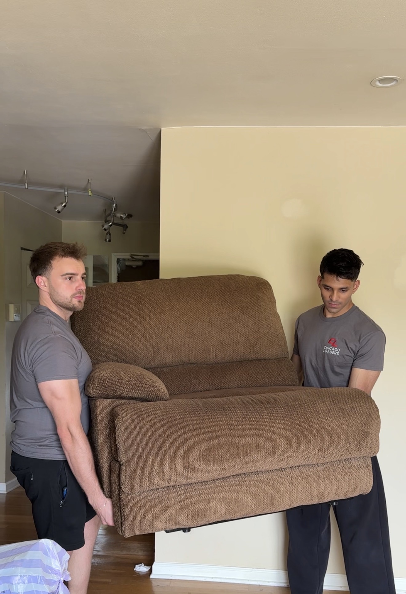 Two Chicago Loaders team members carrying a recliner through a home