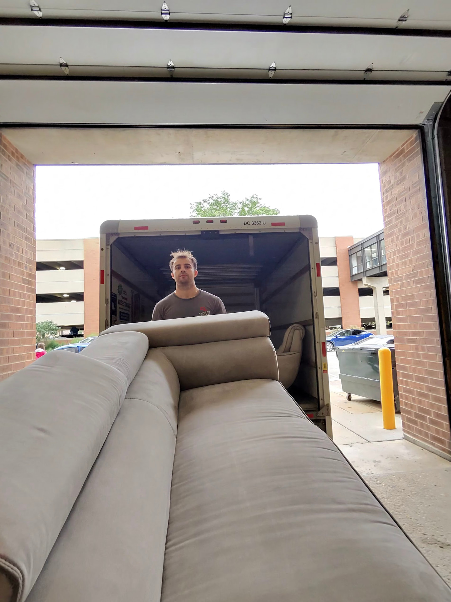 Mover standing in a garage with a fully loaded and organized stack of moving boxes