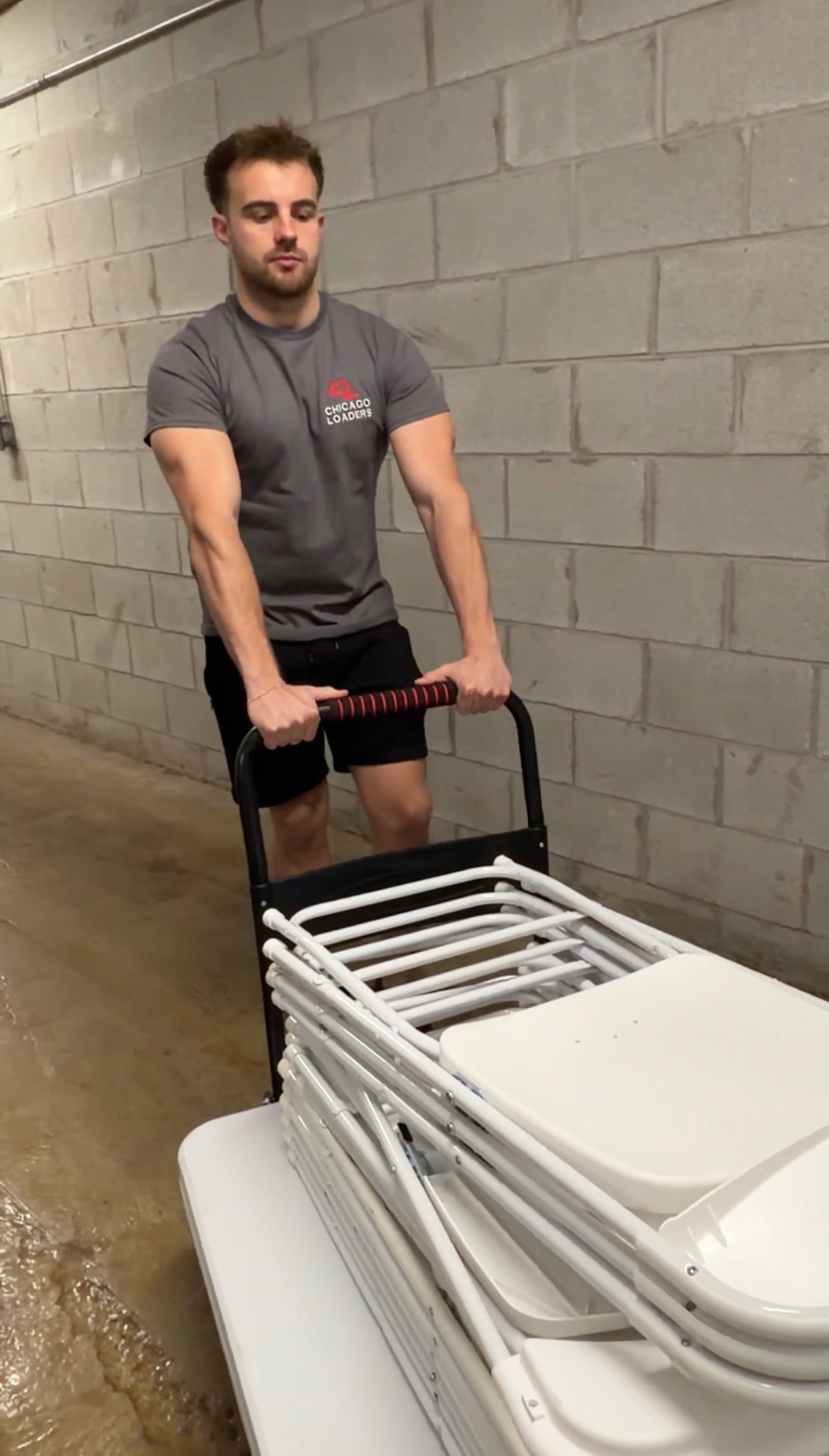 Loader moving a stack of folding tables and chairs on a dolly